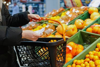 Person at supermarket holding a shopping basket and shopping list