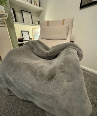 Cozy Earth Cuddle Blanket on a cream armchair.