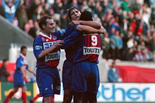 George Weah celebrates a goal for Paris Saint-Germain with team-mates Jose Cobos and David Ginola in May 1994.