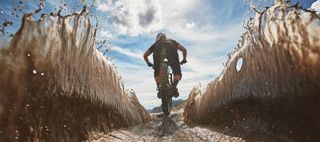 A mountain biker rides through a muddy puddle