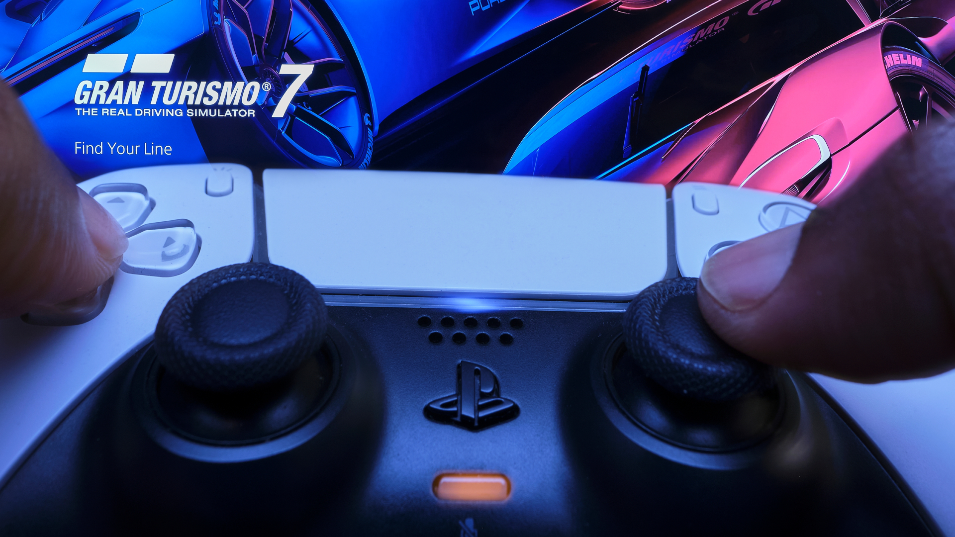 PS5 DualSense controller pointed at a TV displaying Gran Turismo 7 dashboard
