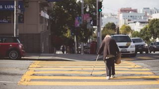an elderly person crossing a road