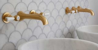 Close up image of a pair of brass taps in a neutral bathroom to show how to make a bathroom look expensive