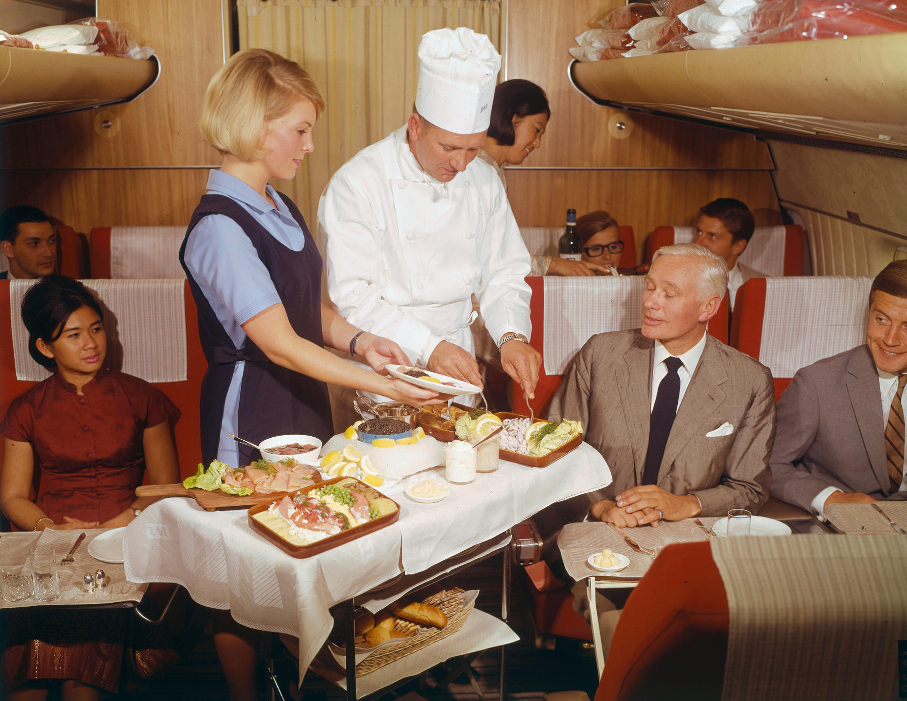 An air stewardess and chef serve lunch from a trolley on board a plane, in the First Class cabin