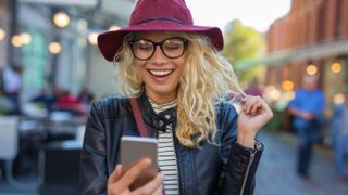 Una mujer mira su teléfono en público y se ríe.