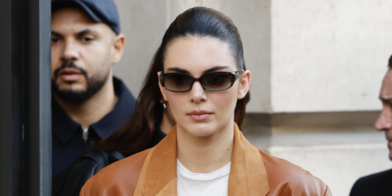 Kendall Jenner wears white top, brown leather double blazer, brown suede Hermès bag, black trousers, black boots, black sunglasses, outside Schiaparelli, during Haute Couture Spring-Summer 2025 as part of Paris Fashion Week on January 27, 2025 in Paris, France