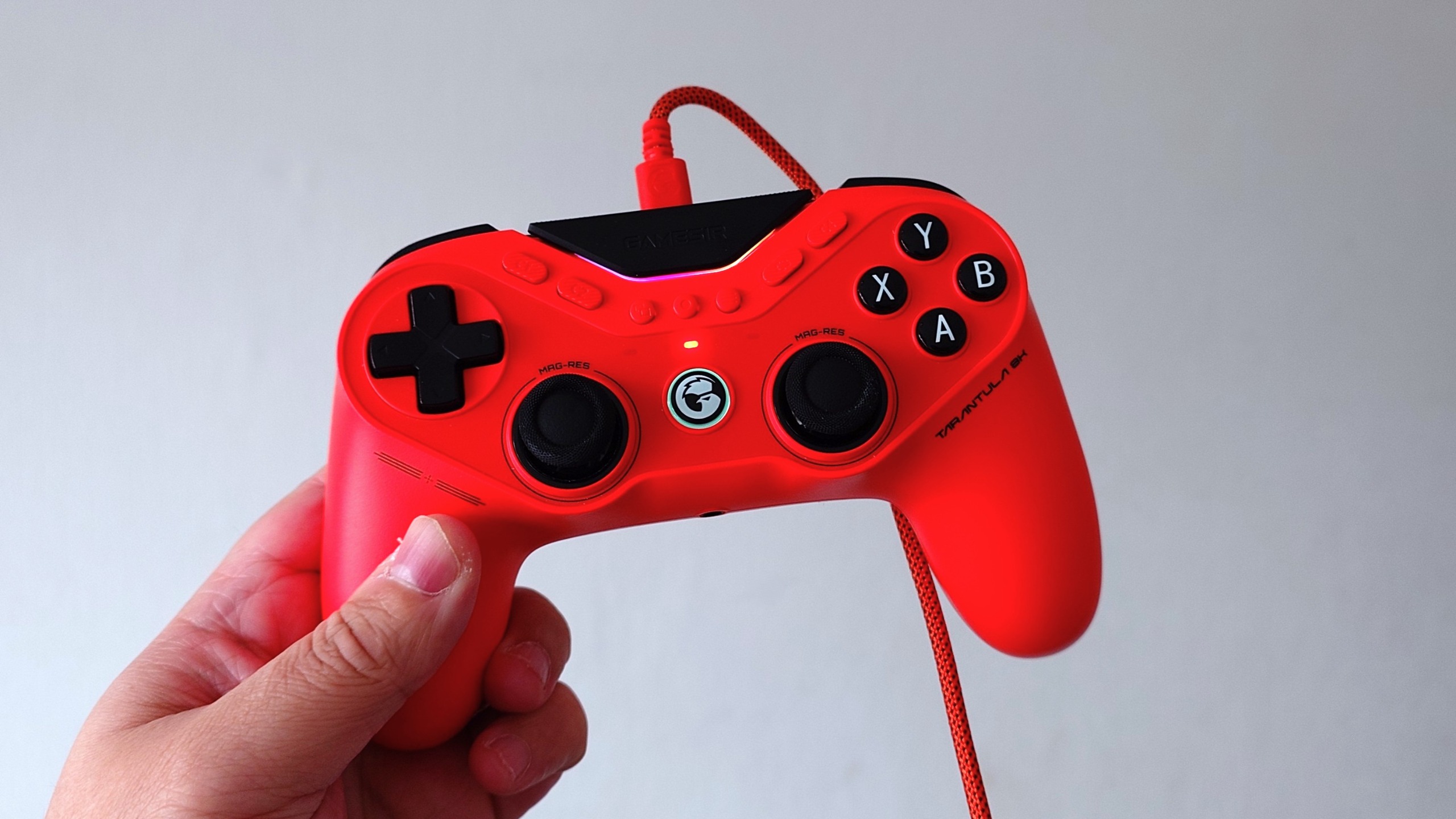 A photo of an orange GameSir Tarantula 8K controller being held in front of a white wall. 