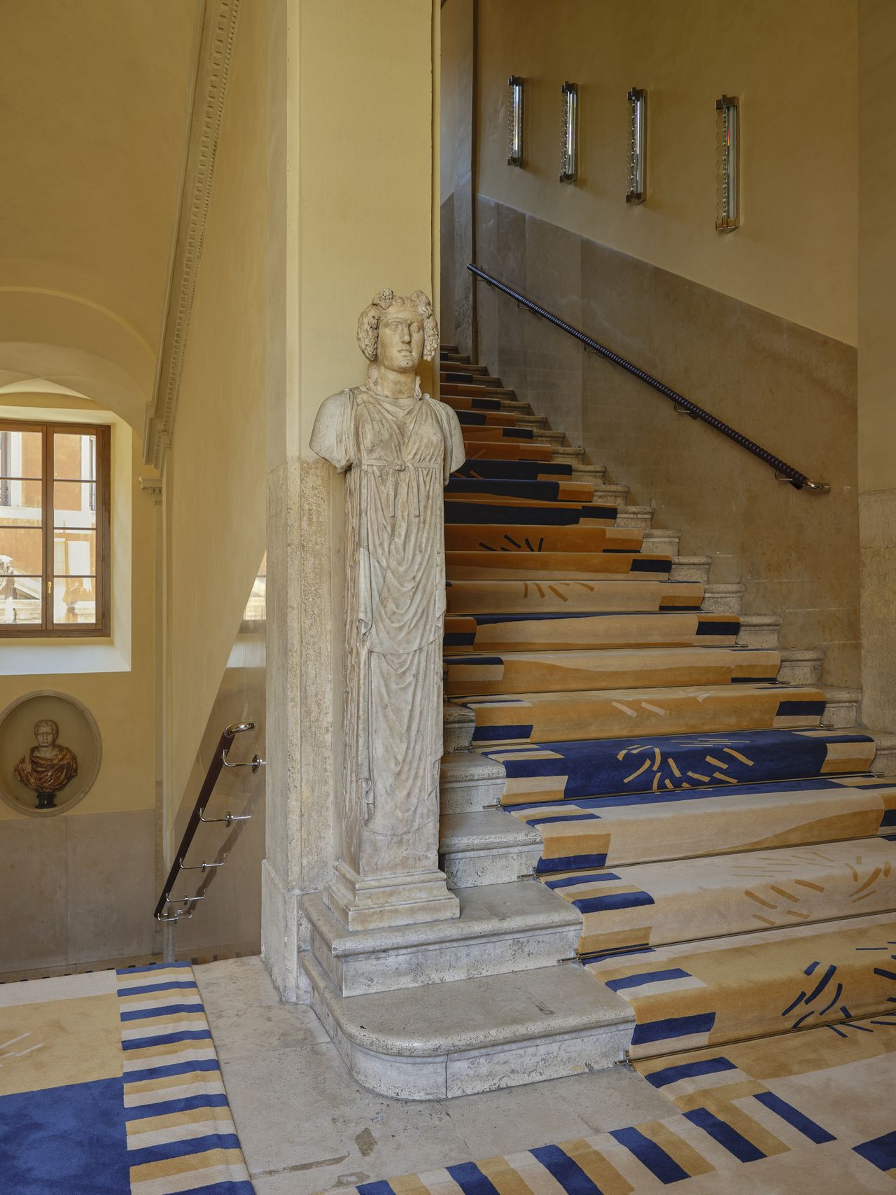 A statues and rugs-decorated staircase.