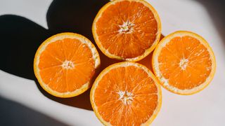 wo oranges in halves casting a shadow on a white surface.