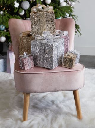 Glittery Christmas gift boxes piled up on a pink chair