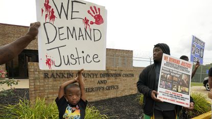 An anti-police brutality activist looks back at the entrance to the Rankin County Sheriff's Office in Brandon, Miss.