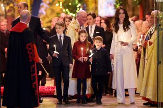 Prince George, Princess Charlotte, Prince Louis and Princess Kate holding candles inside Westminster Abbey during a Christmas carol service