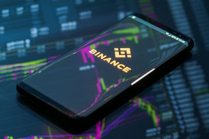 Binance splash screen on a smartphone that's laying on a desk