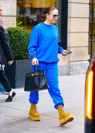 Jennifer Lopez in New York City April 2024 wearing a blue sweatsuit and tall platform boots.