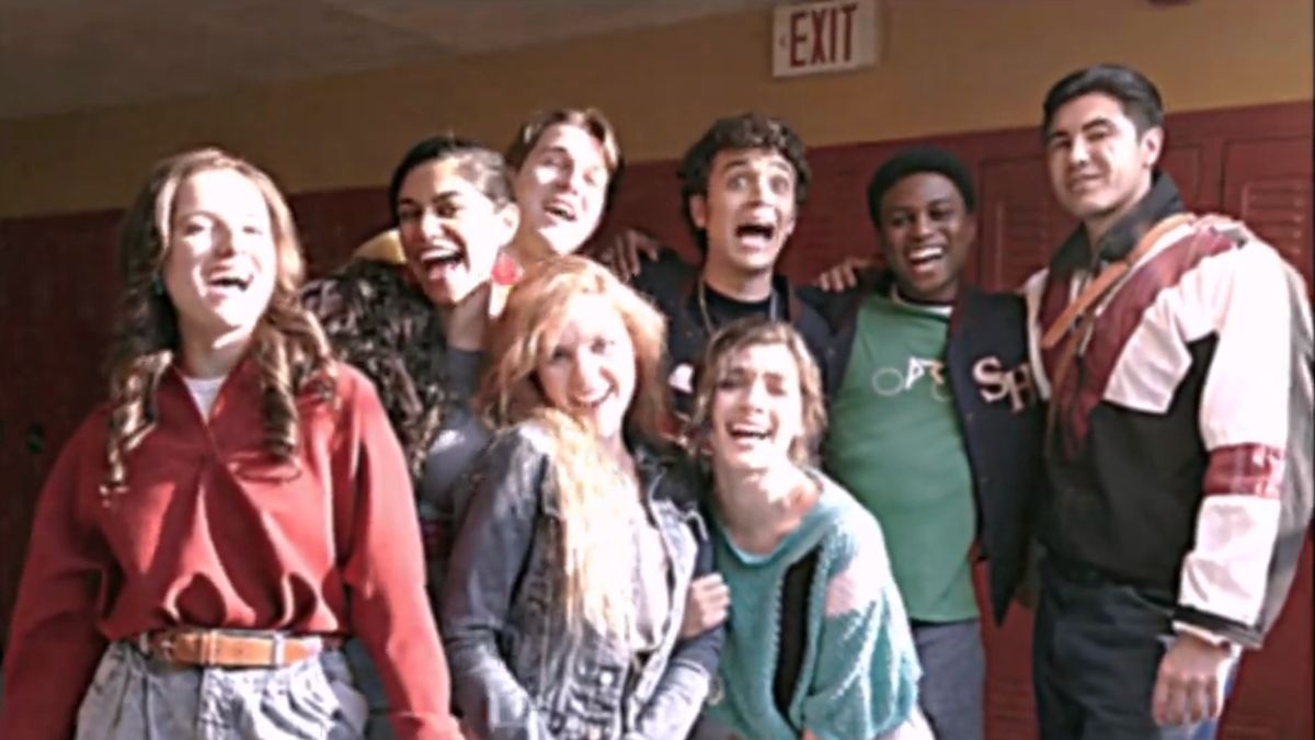 Fear Street: Prom Queen&#039;s cast stands together in high school hallway dressed in 80s costumes.