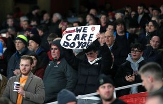 An Arsenal fan holds up a 'We care, do you?' banner