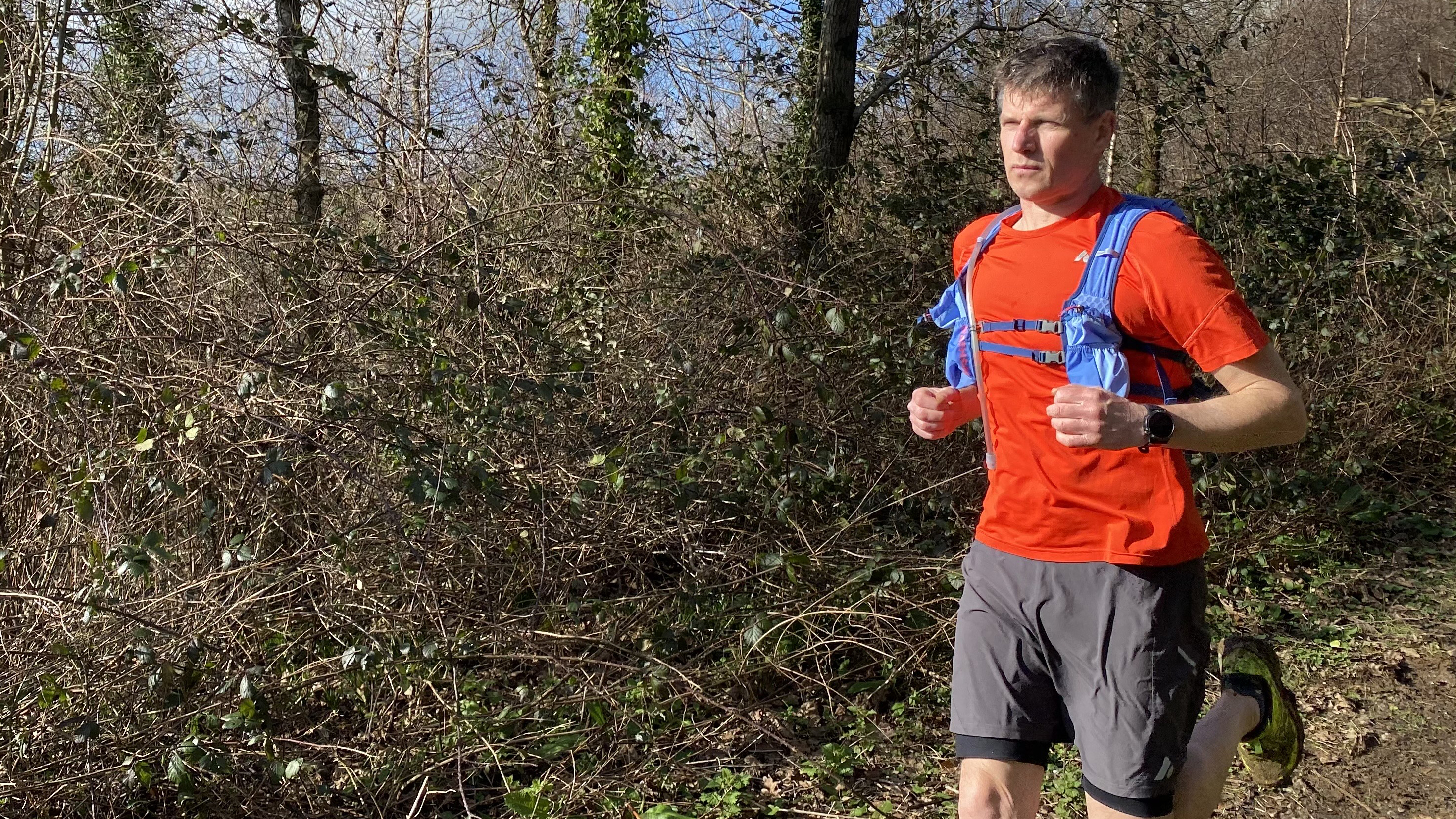 Runner wearing the Nathan TrailMix 2.0 12L Hydration Pack in woods