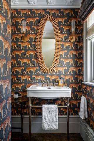 An example of traditional powder room ideas showing leopard walk wallpaper in a bathroom with a white sink