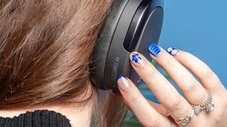 A pair of black Edifier WH950NB over-ear headphones photographed against a blue background