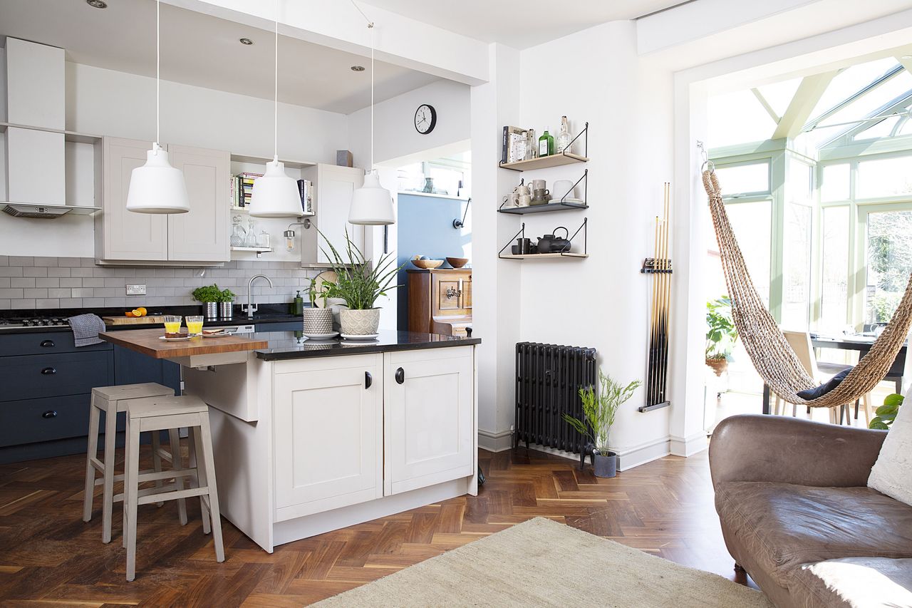 open plan kitchen diner and living area with a shaker style kitchen, leather sofa and parquet flooring