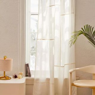 white curtains in a room with a dresser and a chair and a plant