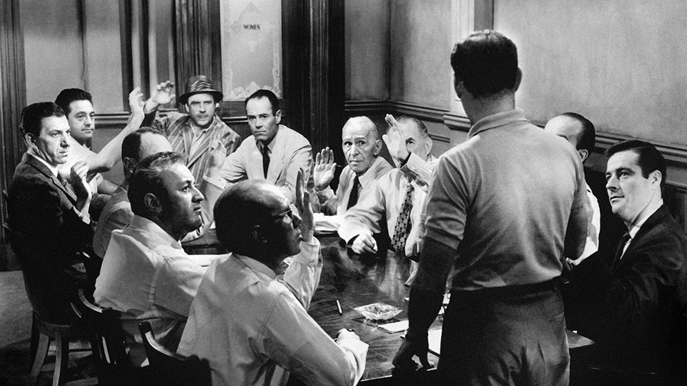 A screenshot take from Sidney Lumet&#039;s 1957 legal drama 12 Angry Men, which shows men voting around a table