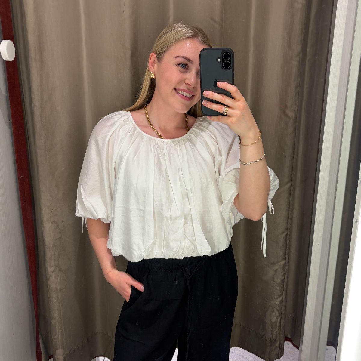 Woman wears white blouse, black trousers
