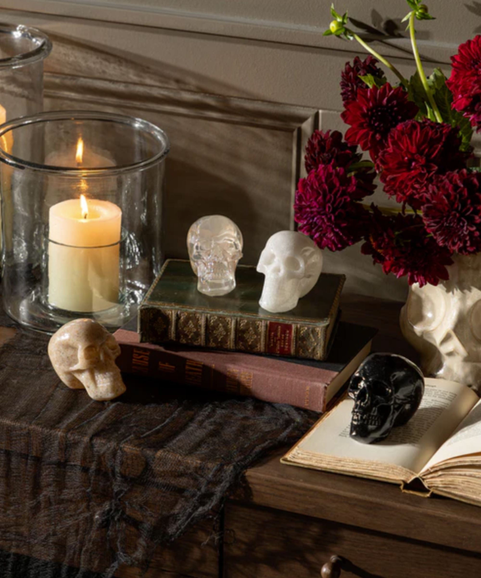 Resin skulls, candles and old books in a halloween vignette