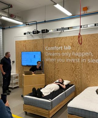 Emilia lying on a mattress against a wooden wall in the IKEA comfort lab.