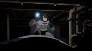 Batman speaks into a walkie talkie while examining a crime scene by flashlight in Batman: Caped Crusader.