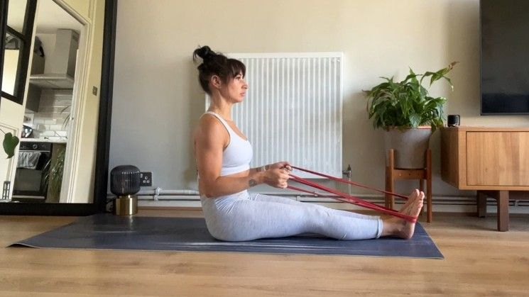 Writer Sam sitting upright at the top of a roll up exercise with band around feet during home workout