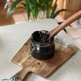 Jar of homemade coffee scrub with wooden spoon