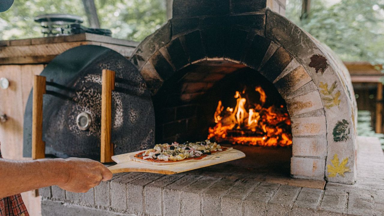 Putting a pizza into a pizza oven 