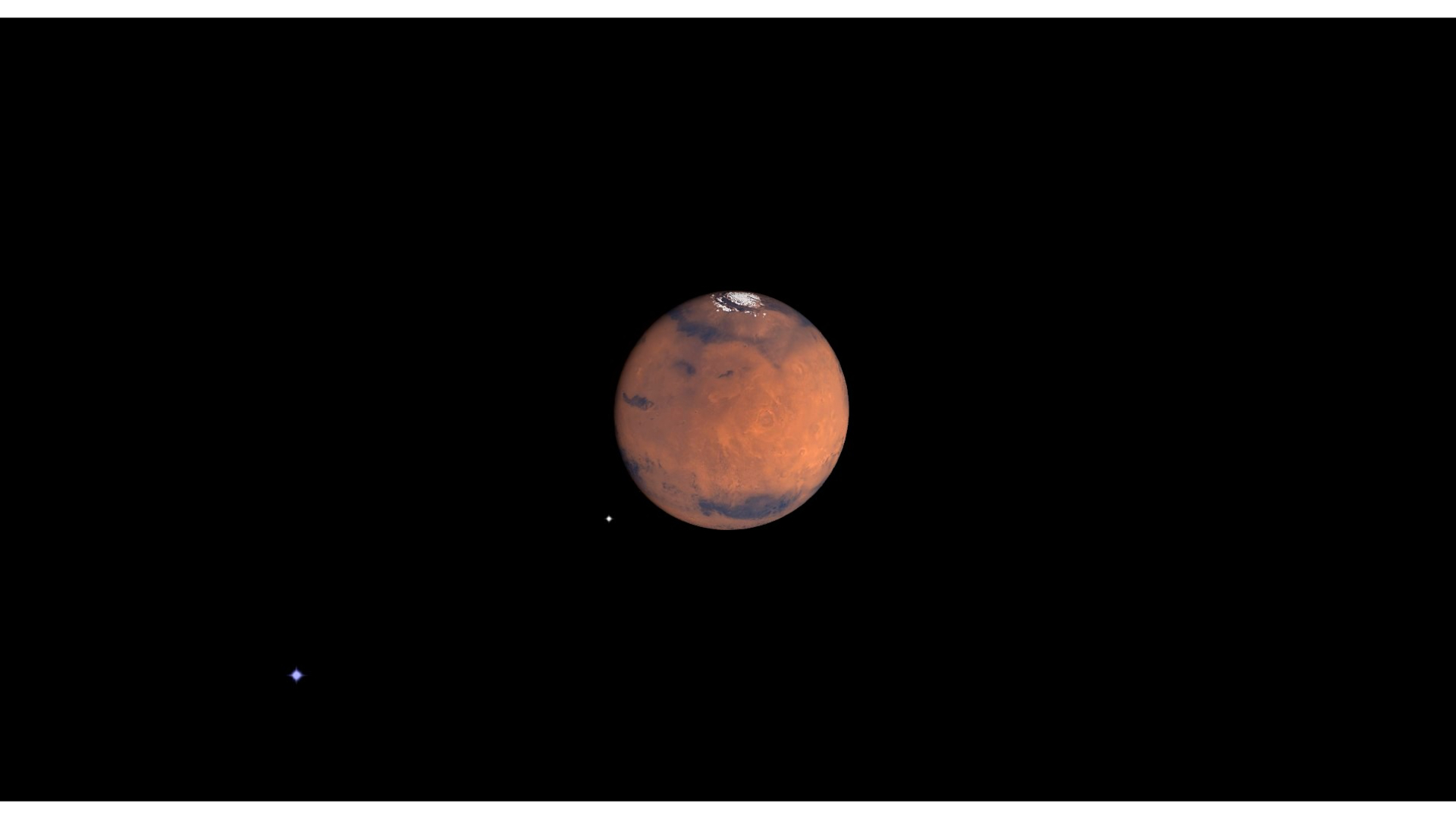 The planet Mars can be seen in the darkness of space. The reddish planet&#039;s icy north pole peeks out from the top of its spherical shape