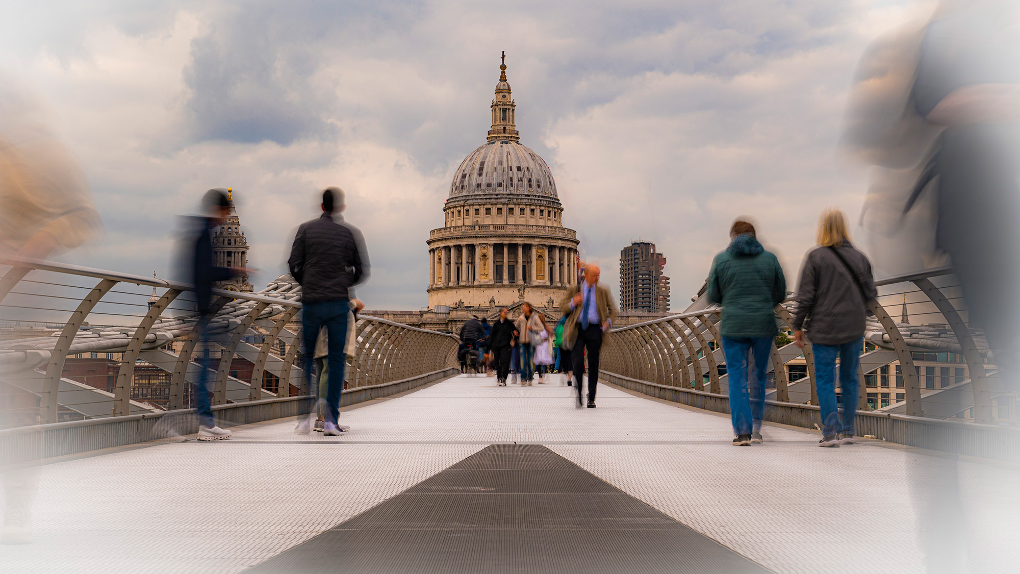 Long exposure of people walking along London&#039;s Millennium Bridge with St Paul&#039;s Cathedral in the background 
