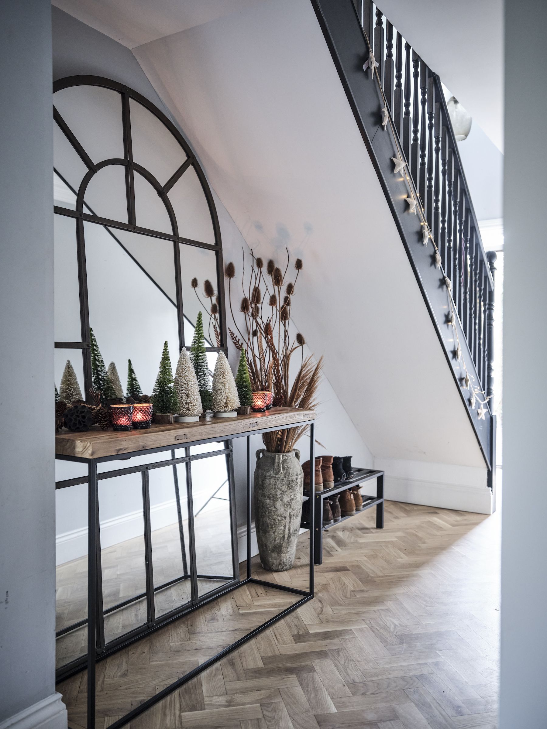 console table with Christmas decorations under stairs