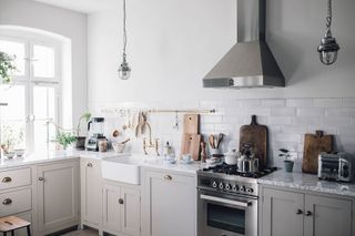 scandi kitchen with pale gray cabinetry and white walls alongside chrome accessories
