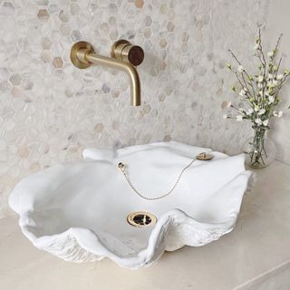 White clam shell bathroom sink with gold hardware