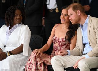 Meghan Markle and price harry sit together while she wears a johanna ortiz dress