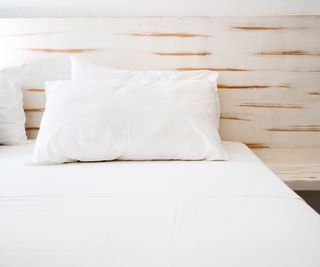 Two pillows on a bed with a wooden bedframe