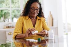 Retired woman carefully taking her prescription medication as part of her daily routine. Mature woman committing to her treatment plan as part of her chronic disease management at home.