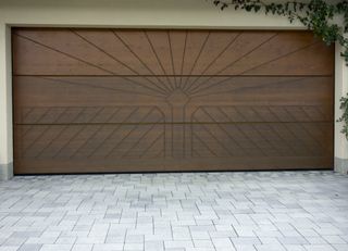 Brown wooden garage door on a green house.