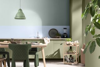 green kitchen with a painted blue splashback and wooden table