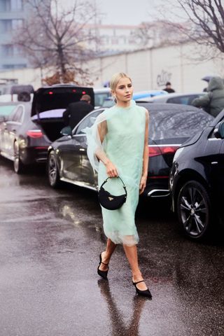 Caroline Daur wearing a mint-green Prada sheer dress with satin heels and matching black bag in Milan.