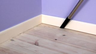 Vacuuming dust on floor next to skirting board