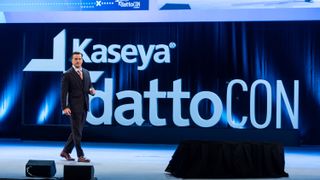 Kaseya CEO Fred Voccola walking across a stage with the Kaseya logo displayed behind him