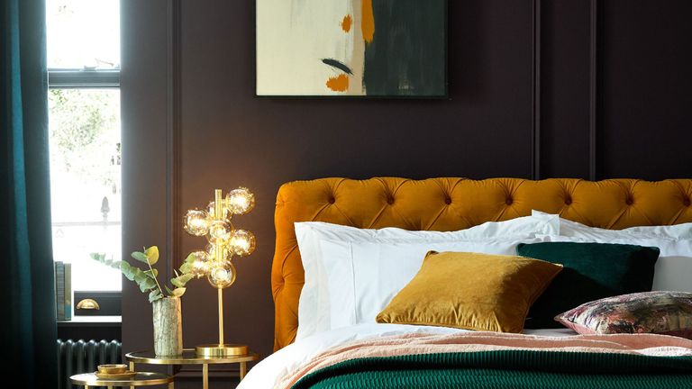 Luxurious black bedroom showcasing the latest bedroom trends 2022 with a mustard velvet button bed frame and abstract artwork