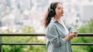 Woman wearing PSB M4U 9 headphones in outdoor setting