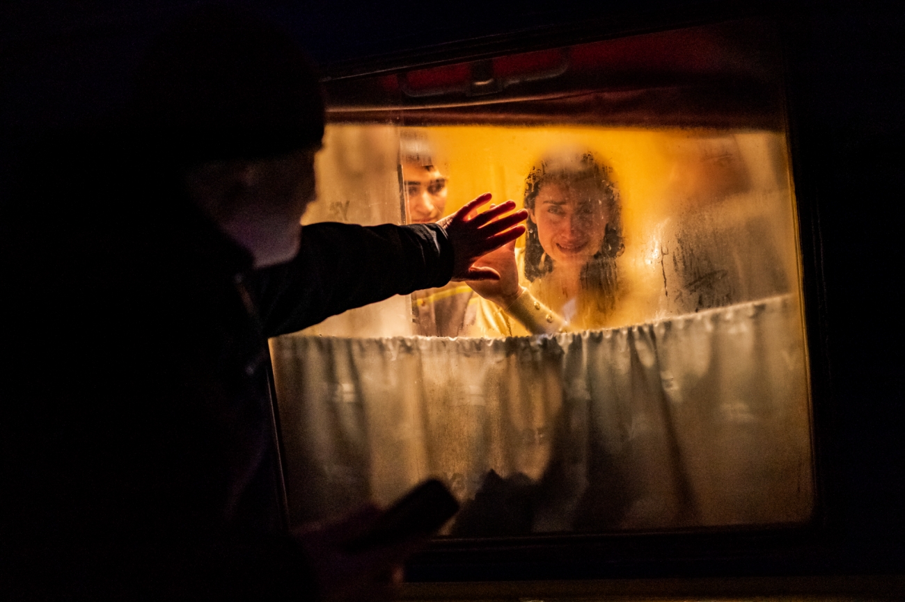 A Ukrainian man bids farewell to his tearful family through a window