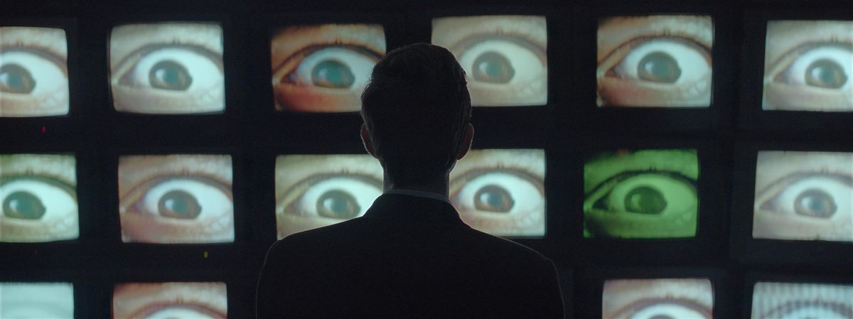 The Antenna: Mehmet stars at a wall of TVs displaying eyeballs.